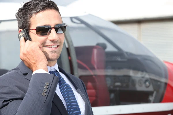 Бизнесмен, пользующийся мобильным телефоном рядом со своим частным самолетом — стоковое фото