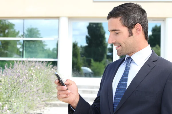 Knappe zakenman tekstberichten op een mobiele telefoon — Stockfoto