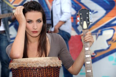 Musician leaning on a drum and holding a guitar clipart