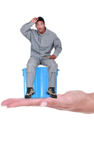 Laborer sitting on a paint can with expression of surprise — Stock Photo, Image