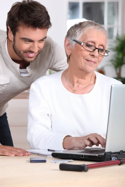 Человек помогает старушке с компьютером — стоковое фото