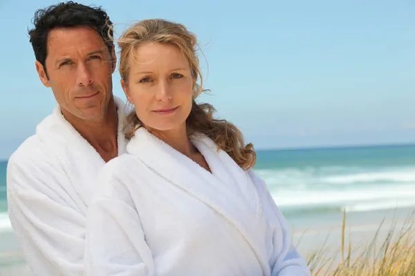 Муж и жена на пляже в халатах — стоковое фото