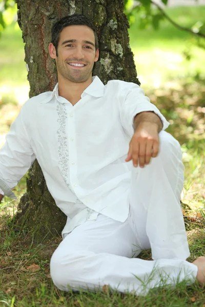 Людина в білому, що розслабляється на дереві — стокове фото