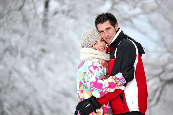 Пара в лижних куртках обіймає зимовий день — стокове фото
