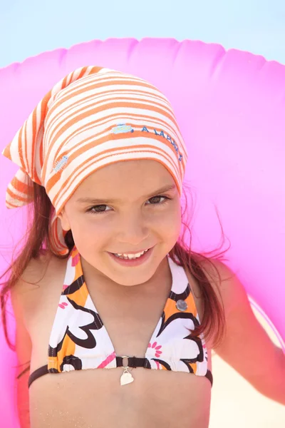 Menina nova em um biquíni com um anel de praia inflável rosa — Fotografia de Stock