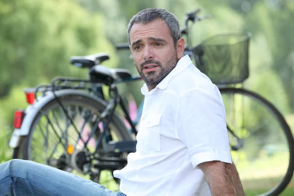 Мужчина сидел, расслабляясь рядом с велосипедом — стоковое фото