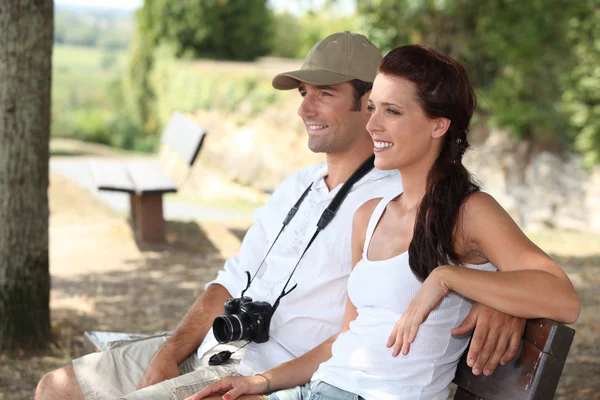 Couple with camera sat on bench — Stock Photo, Image