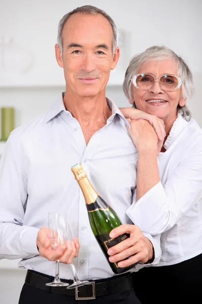 Casal sênior inteligente com garrafa de champanhe — Fotografia de Stock