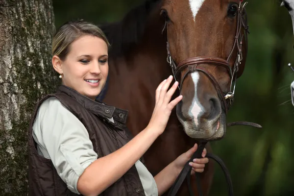 Jonge vrouw strelen van een paard — Stockfoto