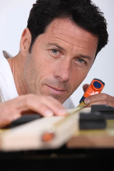 Closeup of a man measuring a piece of wood with a tape measure — Stock Photo, Image
