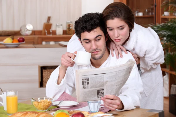Молодая пара читает газету за завтраком — стоковое фото