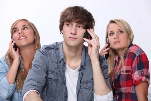 Tre adolescenti che utilizzano telefoni cellulari — Foto Stock