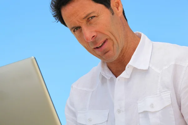 Homem no laptop no céu azul — Fotografia de Stock