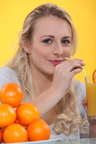 빨 대로 오렌지 주스의 유리를 마시는 여자 — 스톡 사진