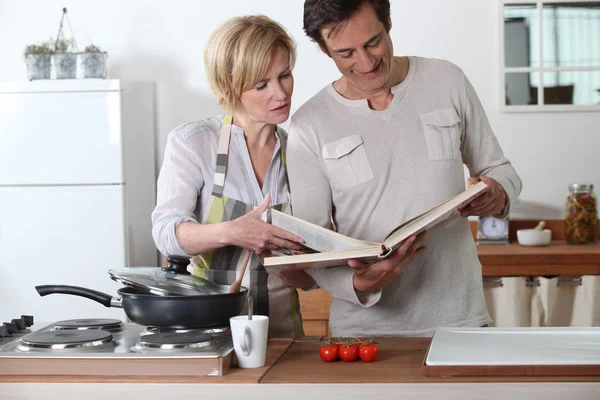 Couple cuisine avec un livre de recettes — Photo
