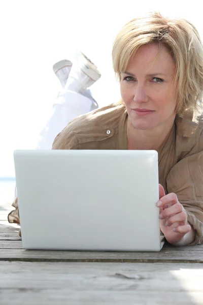 여자는 노트북 컴퓨터와 나무 갑판에 누워 — 스톡 사진