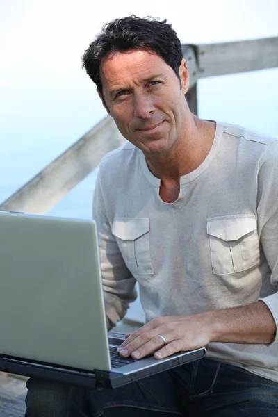 Uomo che lavora al computer portatile in riva al mare — Foto Stock