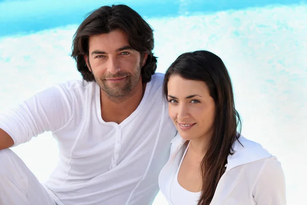 Couple portant des vêtements blancs assis près de la piscine — Photo