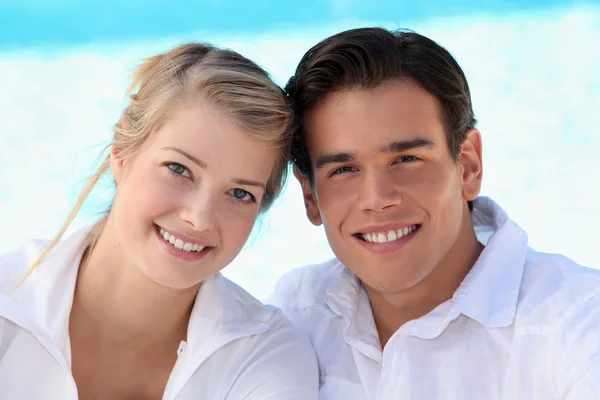 Smiling young couple sitting in the sunshine — Stock Photo, Image