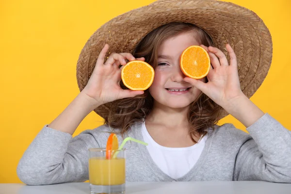 Young girl playing with oranges and drinking orange juice — Stock Photo, Image