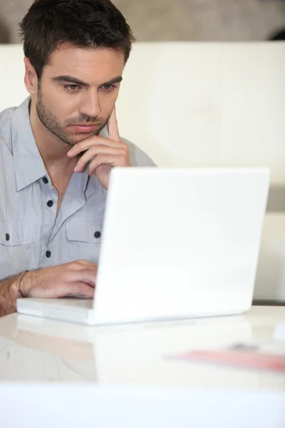 Hombre pensativo usando el ordenador portátil en casa Fotos de stock