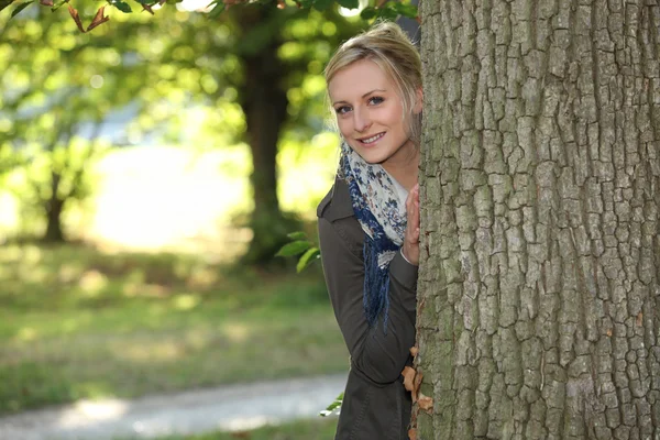 Woman hiding behind a tree Stock Picture