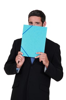 Smiling man hiding behind a folder clipart