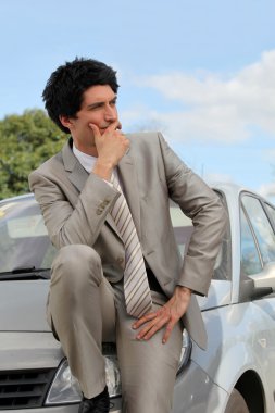 Businessman thinking by his car clipart