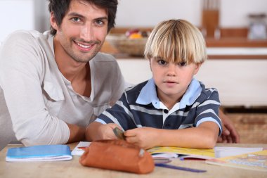 Little boy coloring with his father clipart