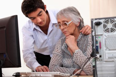 Young man showing elderly lady how to use computer clipart