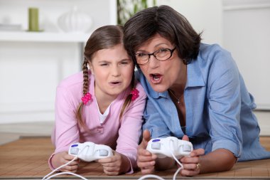 Little girl playing a computer game with her grandma clipart