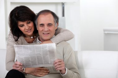 Mature couple reading a newspaper clipart