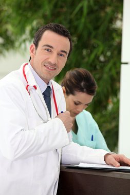 Doctor filling in a patient's record clipart