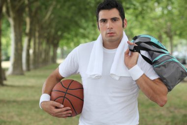 30 years old sportyman holding a basket ball and a sports bag clipart