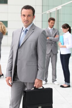 Man with briefcase outside office building clipart