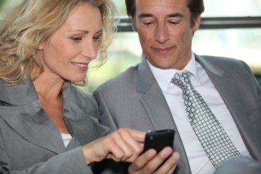 Pair of executives looking at something on a cellphone clipart
