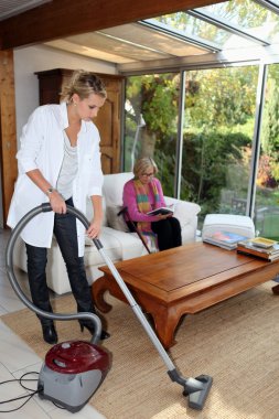 Girl vacuuming for an elderly woman clipart