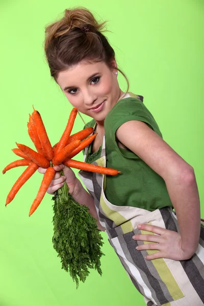 Menina bonita segurando cenouras no fundo verde — Fotografia de Stock