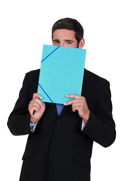 Smiling man hiding behind a folder — Stock Photo, Image
