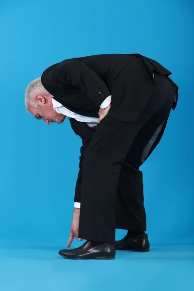 Businessman bent over pointing at shoes — Stock Photo, Image