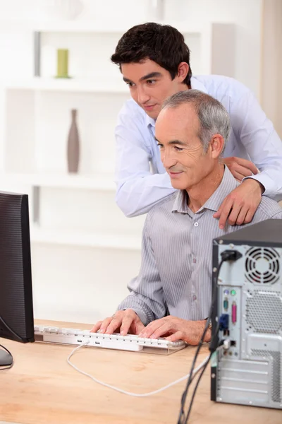 Отец и сын смотрят на экран компьютера . — стоковое фото