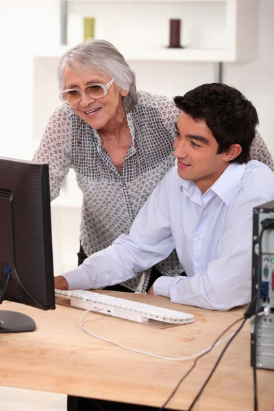 Stará dáma a mladý muž seděl u počítače — Stock fotografie