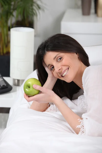 Mulher comendo uma maçã em seu treinador — Fotografia de Stock