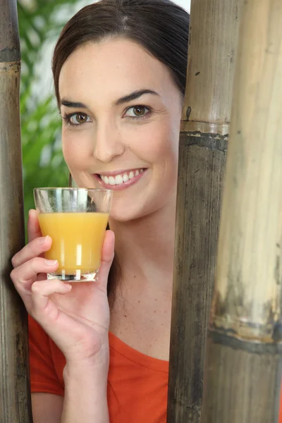 Улыбающаяся женщина со стаканом апельсинового сока — стоковое фото