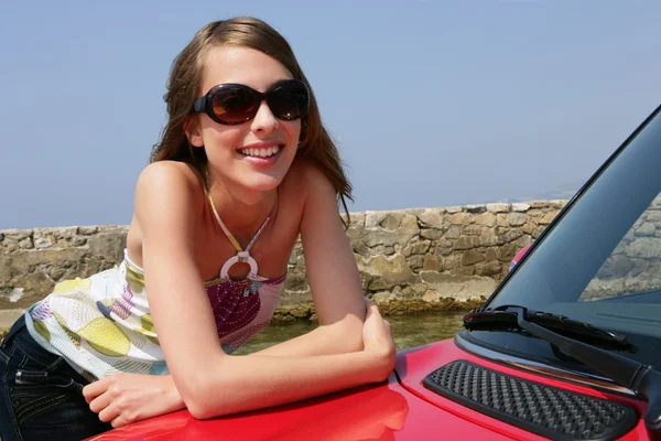 Młoda kobieta nachylając się przed samochód — Zdjęcie stockowe