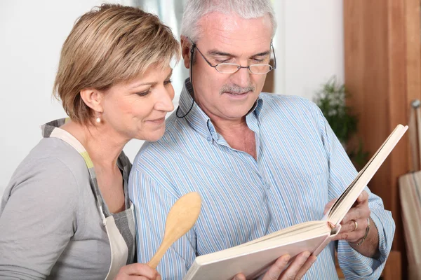 Älteres Paar schaut sich ein Rezeptbuch an — Stockfoto