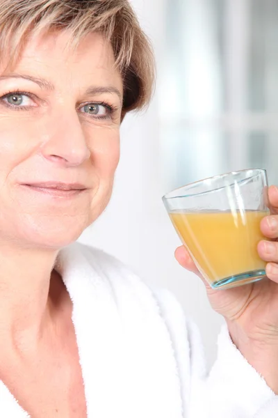 Зрелая женщина со стаканом апельсинового сока — стоковое фото