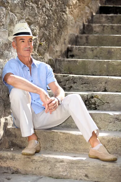 Muž středního věku seděl na staré kamenné schody — Stock fotografie