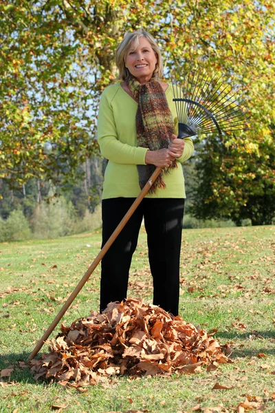 Femme ratissant les feuilles d'automne — Photo