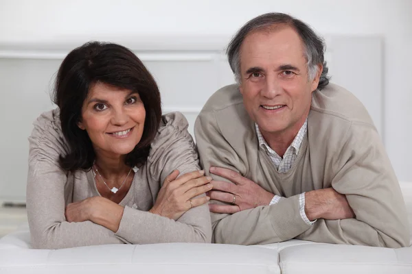 A middle age couple laying on their bed. — Stock Photo, Image